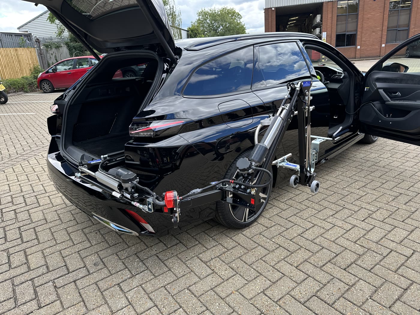 Abi Loader arm extended out of the boot alongside a black estate car