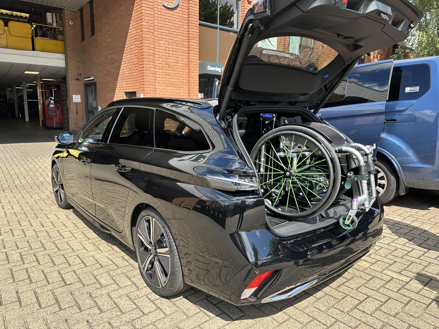 Wheelchair loaded in the boot of a black estate car by an Abi Loader with the rear hatch open